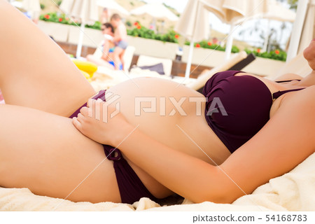 Pregnant woman relaxing on sunbed on the beach resort, healthy pregnancy concept Pregnant woman relaxing on sunbed on the beach resort, healthy pregnancy concept 54168783