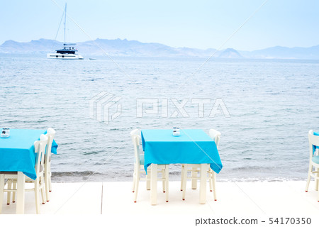 Cafe tables served with a blue tablecloth near the sea coast for relaxing holidays vacations 54170350