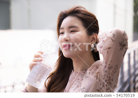 A woman drinking water from a water bottle 54170519