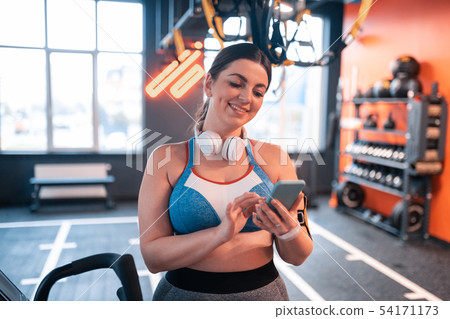 Young woman reading messages on phone before workout Young woman reading messages on phone before workout 54171173