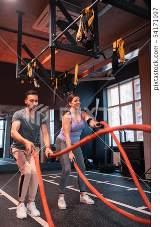Plump woman wearing leggings having workout in gym with TRX Plump woman wearing leggings having workout in gym with TRX 54171997