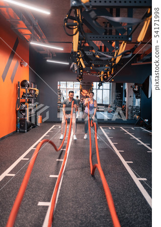 Trainer and overweight woman using TRX straps for cardio Trainer and overweight woman using TRX straps for cardio 54171998