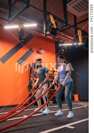 Woman with overweight exercising with TRX near her trainer 54171999