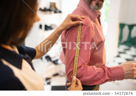 Close-up shot of woman getting measurements of adult stylish man Close-up shot of woman getting measurements of adult stylish man 54172674