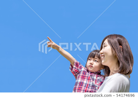A little girl holding a mother against the blue sky and pointing to the upper left. 54174696
