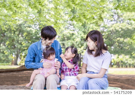 凝視照相機的四個家庭在新鮮的綠色公園。快樂，愛心的形象 54175209