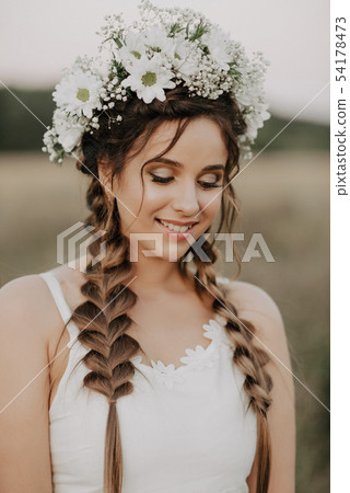 happy smiling girl with braids and floral wreath in white dress in boho style in summer outdoors happy smiling girl with braids and floral wreath in white dress in boho style in summer outdoors 54178473