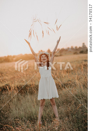 Happy girl in white dress plays and enjoys summer in the field Happy girl in white dress plays and enjoys summer in the field 54178517