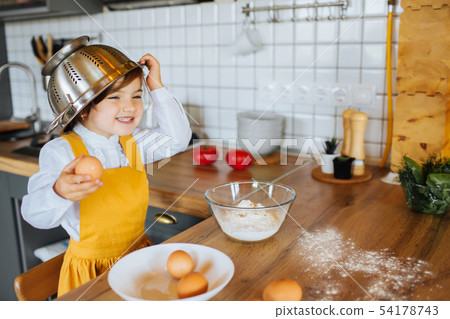 Little happy girl helps to bake cookies in the kitchen. Little happy girl helps to bake cookies in the kitchen. 54178743