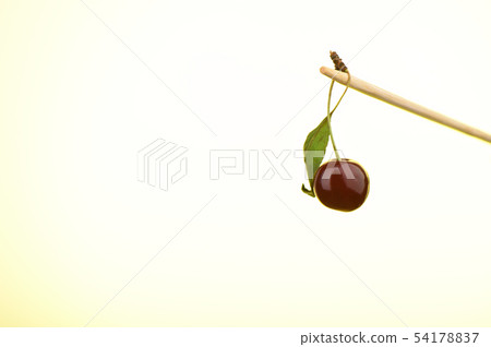 Ripe cherry on a stick with a yellow backlit 54178837