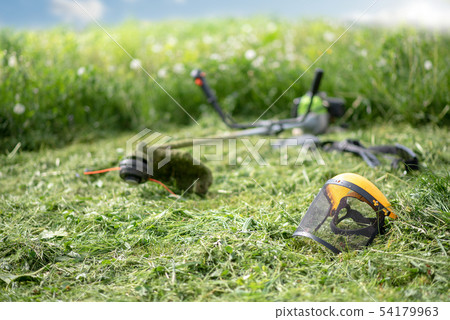 String trimmer and protective face mask on mown grass String trimmer and protective face mask on mown grass 54179963