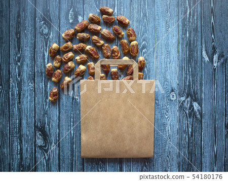 Paper bag with scattered dates on a dark table Paper bag with scattered dates on a dark table 54180176