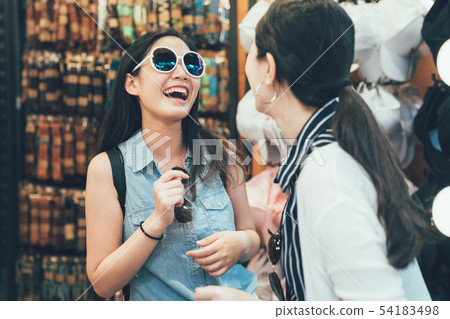 women smiling trying sunglasses with friend women smiling trying sunglasses with friend 54183498