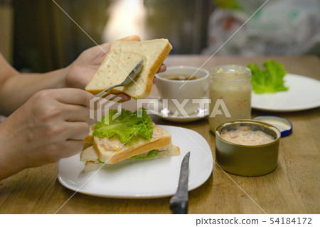 hands spreading tuna mayonnaise on bread for 54184172