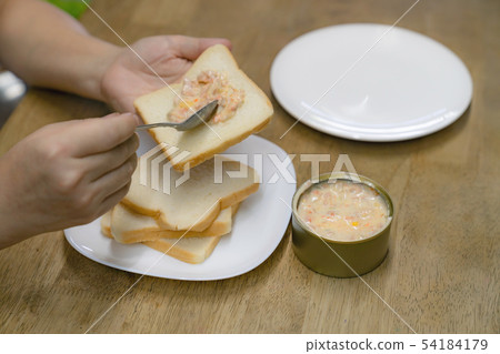 hands spreading tuna mayonnaise on bread for hands spreading tuna mayonnaise on bread for 54184179