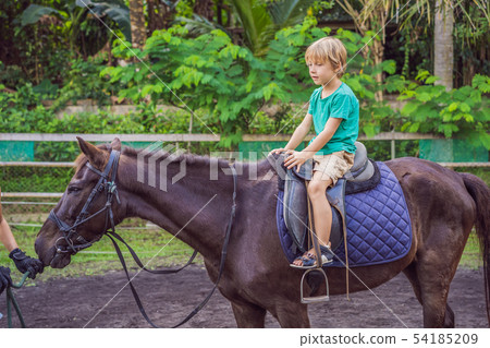 Boy horseback riding, performing exercises on horseback Boy horseback riding, performing exercises on horseback 54185209