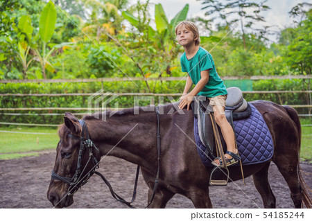 Boy horseback riding, performing exercises on horseback Boy horseback riding, performing exercises on horseback 54185244