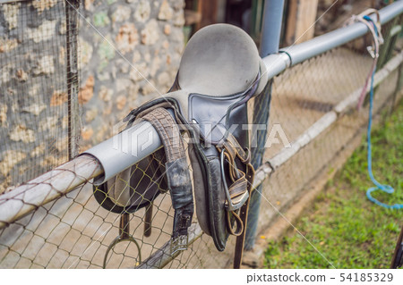 A saddle laying on the rustic fence in warm day A saddle laying on the rustic fence in warm day 54185329