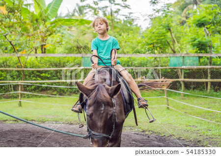 Boy horseback riding, performing exercises on horseback Boy horseback riding, performing exercises on horseback 54185330