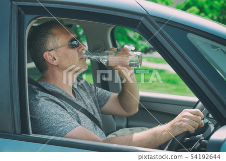 Man drinking alcohol while driving a car Man drinking alcohol while driving a car 54192644