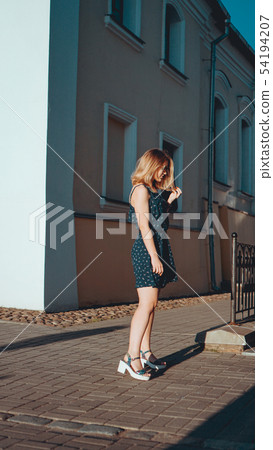 Woman in dress walks through the old city streets on a sunny day Woman in dress walks through the old city streets on a sunny day 54194207