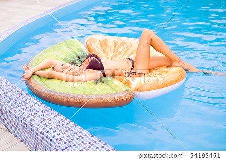 Beautiful young woman swims in the pool on 54195451