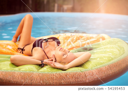 Beautiful young woman swims in the pool on 54195453