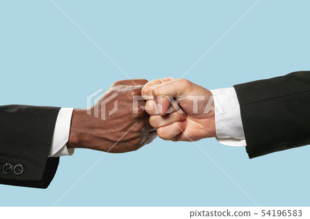 Two male hands competion in arm wrestling isolated on blue studio background Two male hands competion in arm wrestling isolated on blue studio background 54196583