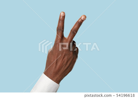 Male hand demonstrating a gesture of peace isolated on blue background 54196618