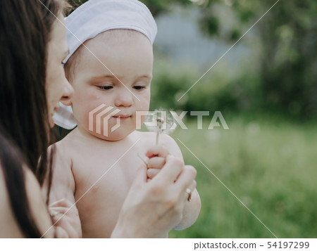 baby boy with mom playing dandelion flower in summer 54197299