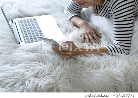 girl lying on the bed play her smartphone 54197778