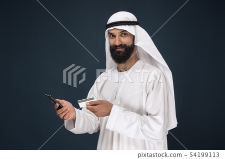 Arabian saudi man on dark blue studio background Arabian saudi man on dark blue studio background 54199113