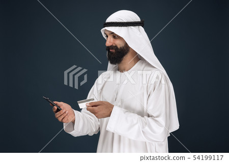 Arabian saudi man on dark blue studio background Arabian saudi man on dark blue studio background 54199117