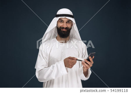 Arabian saudi man on dark blue studio background Arabian saudi man on dark blue studio background 54199118