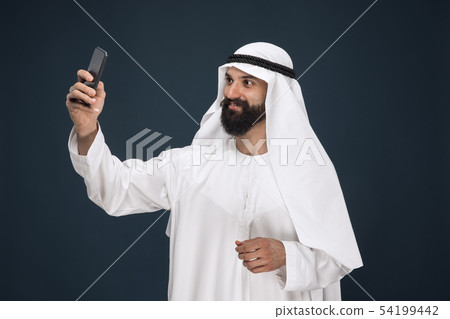Arabian saudi man on dark blue studio background Arabian saudi man on dark blue studio background 54199442