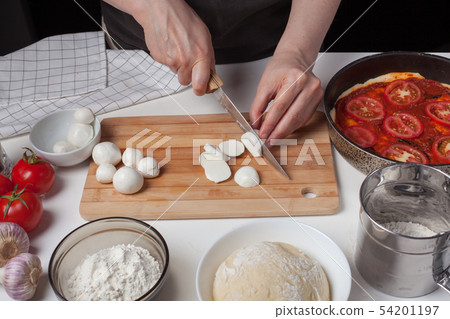 A woman chef slices mozzarella cheese. A woman chef slices mozzarella cheese. 54201197