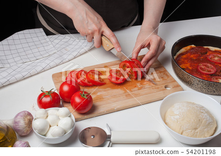 Female chef cuts the tomatoes. Female chef cuts the tomatoes. 54201198