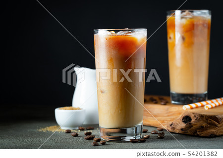 Ice coffee in a tall glass with cream poured over. Ice coffee in a tall glass with cream poured over. 54201382