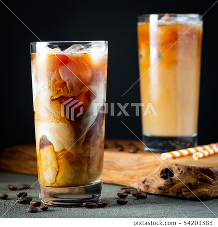 Ice coffee in a tall glass with cream poured over. Ice coffee in a tall glass with cream poured over. 54201383