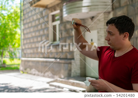 The man in the street rubs his glasses 54201480