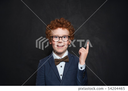 Happy redhead boy pointing up on chalkboard 54204465