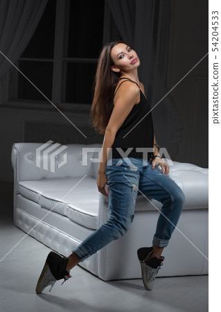 Attractive brunette posing sitting on a sofa. Attractive brunette posing sitting on a sofa. 54204533