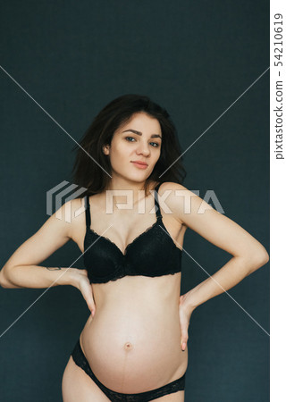 Pregnant young beautiful brunette girl posing in lingerie Pregnant young beautiful brunette girl posing in lingerie 54210619