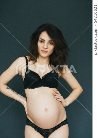 Pregnant young beautiful brunette girl posing in lingerie Pregnant young beautiful brunette girl posing in lingerie 54210621