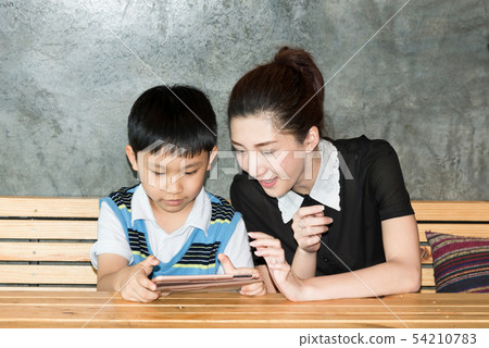 Mother and son playing with digital tablet at home 54210783