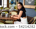Girl with blue eyes sitting on urban cafe using 54214282