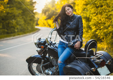 attractive brunette motorcyclist sits on a motorcycle. attractive brunette motorcyclist sits on a motorcycle. 54216546