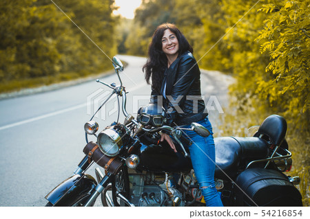 attractive brunette motorcyclist sits on a motorcycle. 54216854