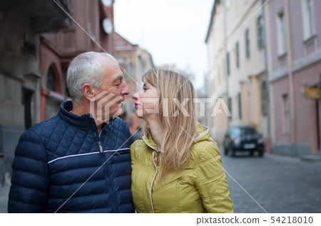 Portrait of happy romantic couple with age difference kissing outdoors in the ancient city during 54218010