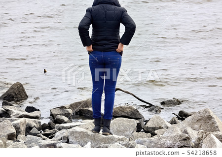 Young woman in blue jeans looks at the sea Young woman in blue jeans looks at the sea 54218658